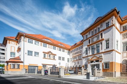 Detailreiche Jugendstilfassade des Dorotheum Linz mit aufwendig verzierten Fenstern, geometrischen Ornamenten und markanten orangefarbenen Zierelementen, restauriert mit Histolith-Farben