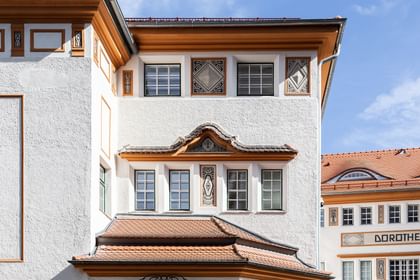 Detailreiche Jugendstilfassade des Dorotheum Linz mit aufwendig verzierten Fenstern, geometrischen Ornamenten und markanten orangefarbenen Zierelementen, restauriert mit Histolith-Farben