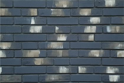 Dunkle Klinker mit ausdrucksstarker Patina verleihen der Wand eine markante Lebendigkeit