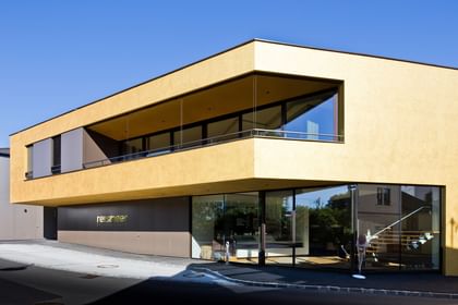 Modernes Gebäude der Bäckerei Reisinger in Gutau mit großzügigen Glasfronten und einer Fassadengestaltung mit CapaGold.
