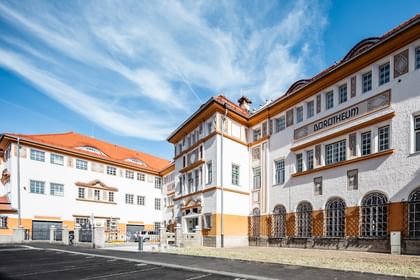 Detailreiche Jugendstilfassade des Dorotheum Linz mit aufwendig verzierten Fenstern, geometrischen Ornamenten und markanten orangefarbenen Zierelementen, restauriert mit Histolith-Farben