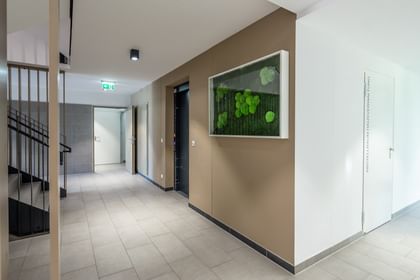 Stiegenhaus mit schwarzem Geländer, Aufzug, braune und weiße Wände