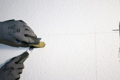 Zwei Hände in Handschuhen, die die Bohrlöcher mit Injektionsstopfen verschließen