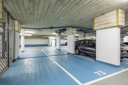Tiefgarage mit weißen Säulen, blauen Parkflächen und Autos