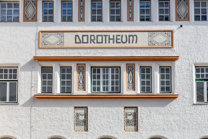 Detailreiche Jugendstilfassade des Dorotheum Linz mit aufwendig verzierten Fenstern, geometrischen Ornamenten und markanten orangefarbenen Zierelementen, restauriert mit Histolith-Farben