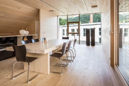 Modernes Wohnzimmer aus Holz mit großem Tisch, schwarzen Stühlen und Panoramafenster