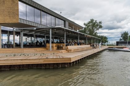 Sitzmöglichkeiten aus Holz vor dem Restaurant mit Blick auf den See