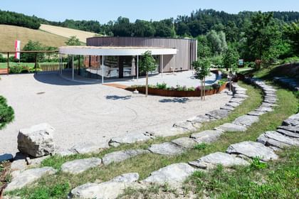 Gebäude mit Holzfassaden, das von einer gepflegten Landschaft umgeben ist. 