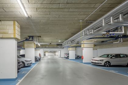 Tiefgarage mit weißen Säulen, blaue Parkflächen und Autos