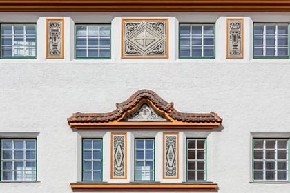Detailreiche Jugendstilfassade des Dorotheum Linz mit aufwendig verzierten Fenstern, geometrischen Ornamenten und markanten orangefarbenen Zierelementen, restauriert mit Histolith-Farben