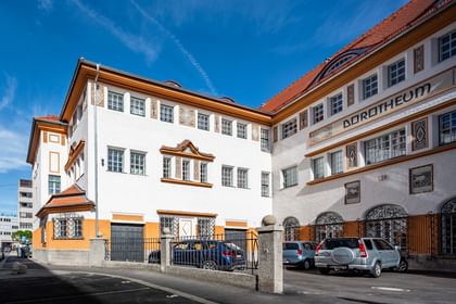 Detailreiche Jugendstilfassade des Dorotheum Linz mit aufwendig verzierten Fenstern, geometrischen Ornamenten und markanten orangefarbenen Zierelementen, restauriert mit Histolith-Farben