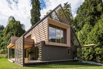 Außenansicht eines modernen Passivhauses mit Holzfassade in natürlichem Grauton, großen Fensterflächen und flach geneigtem Dach, aufgenommen bei Tageslicht im Rahmen der NÖ Landesausstellung in Neubruck, Scheibbs.
