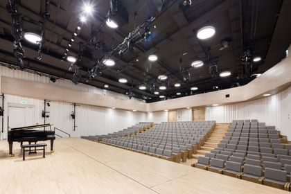 Großer Konzert- oder Vortragssaal in der Anton Bruckner Privatuniversität Linz mit Sitzreihen, einem schwarzen Flügel und klarer, moderner Raumgestaltung, vorbereitet für musikalische oder akademische Veranstaltungen.