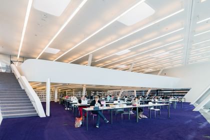 Moderner Bibliotheksraum der Wirtschaftsuniversität Wien mit weißen Wänden, großen Fensterflächen, offenen Arbeitsbereichen und heller Atmosphäre.
