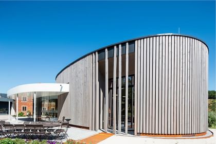 Holzlamellen in organischer Rundung – harmonischer Dialog aus Natur und Architektur