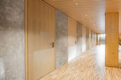 Flur einer Volkshochschule. Entlang des Flurs sind mehrere Türen aus Holz, die in weitere Räume führen.
