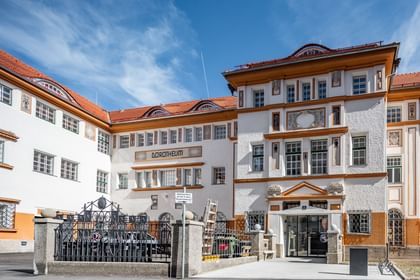 Detailreiche Jugendstilfassade des Dorotheum Linz mit aufwendig verzierten Fenstern, geometrischen Ornamenten und markanten orangefarbenen Zierelementen, restauriert mit Histolith-Farben