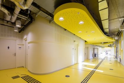 Gang mit gelbem Boden, weiße Wände und industrieller Belüftung an der Decke