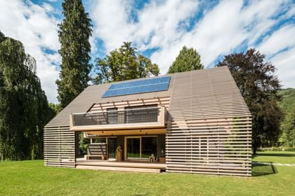 Außenansicht eines modernen Passivhauses mit Holzfassade in natürlichem Grauton, großen Fensterflächen und flach geneigtem Dach, aufgenommen bei Tageslicht im Rahmen der NÖ Landesausstellung in Neubruck, Scheibbs.