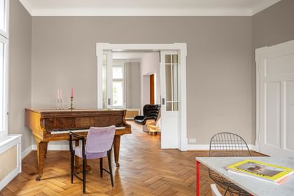 Klavierzimmer mit braunem Klavier und lila Sessel