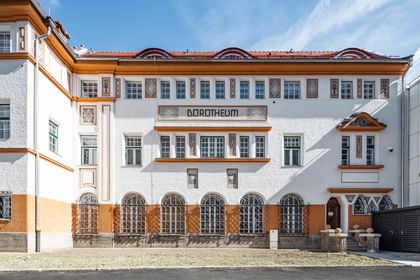 Detailreiche Jugendstilfassade des Dorotheum Linz mit aufwendig verzierten Fenstern, geometrischen Ornamenten und markanten orangefarbenen Zierelementen, restauriert mit Histolith-Farben