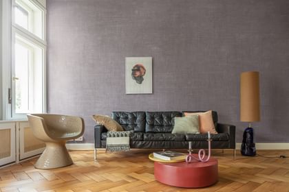 Wohnzimmer mit schwarzen Sofa, beigem Sessel und rotem Beistelltisch