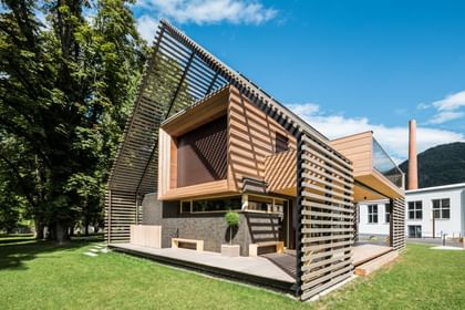 Außenansicht eines modernen Passivhauses mit Holzfassade in natürlichem Grauton, großen Fensterflächen und flach geneigtem Dach, aufgenommen bei Tageslicht im Rahmen der NÖ Landesausstellung in Neubruck, Scheibbs.
