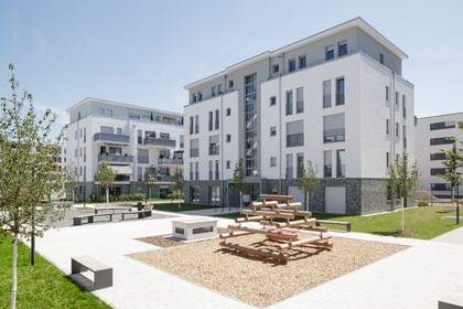 Gebäude von außen mit Kinderklettergerüst und Sitzgelegenheiten