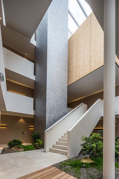 Lichtdurchflutetes Atrium mit Holz, Naturstein und modernem Treppenaufgang
