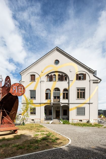 Eingangsbereich des Gebäudes mit davorstehenden rostigen Stahlkonstruktion
