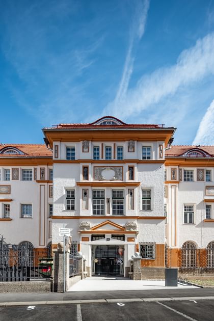 Detailreiche Jugendstilfassade des Dorotheum Linz mit aufwendig verzierten Fenstern, geometrischen Ornamenten und markanten orangefarbenen Zierelementen, restauriert mit Histolith-Farben