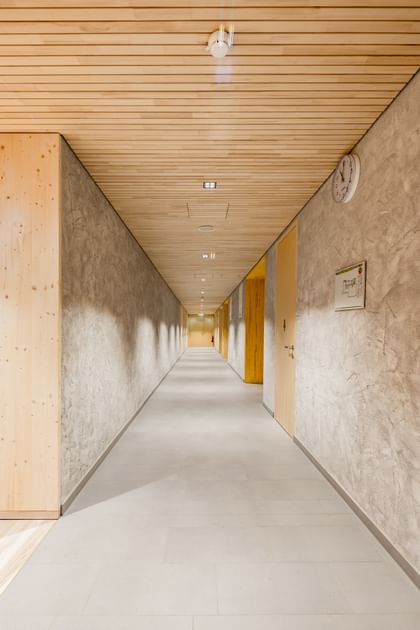 Langer Flur mit Holzdecke und Wänden in Betonoptik
