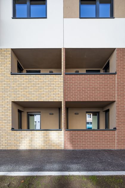 Außenansicht Mehrparteienhaus, Fassade in Klinkeroptik, links beige und rechts braun, mit Loggias
