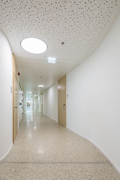 Heller, moderner Flur mit weißen Wänden, rundem Deckenlicht und mehreren Türen in der Anton Bruckner Privatuniversität
