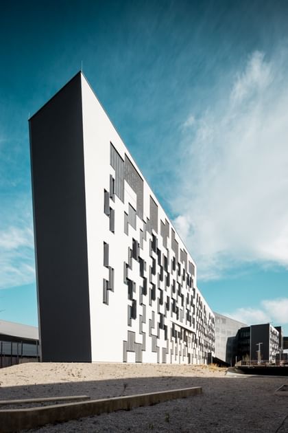Modernes Gebäude der Wirtschaftsuniversität Wien mit weißer, geometrischer Fassade und unregelmäßig angeordneten Fenstern.