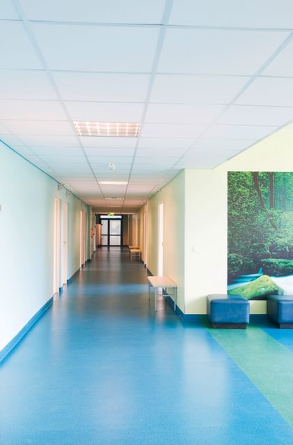 Hygienisch, freundlich, sicher – Klinikflur mit pflegeleichtem, blauem Boden und Naturbild