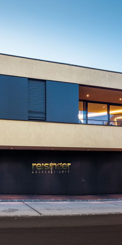Modernes Gebäude der Bäckerei Reisinger in Gutau mit großzügigen Glasfronten und einer Fassadengestaltung mit CapaGold.