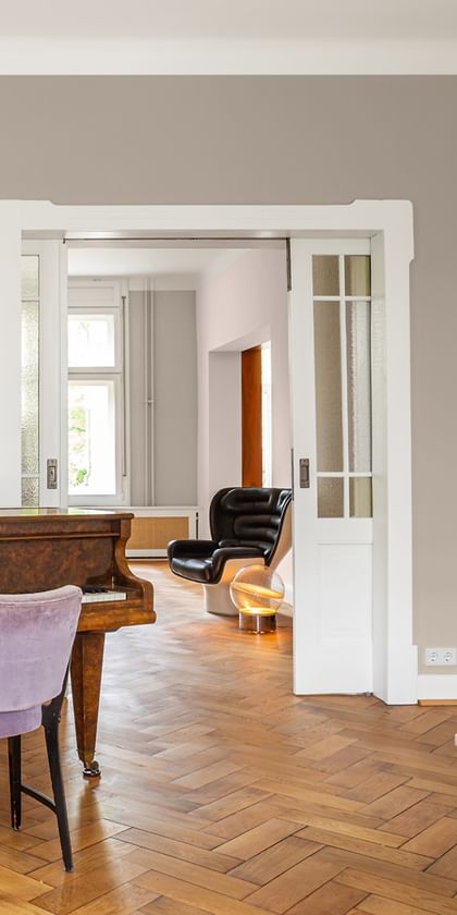 Klavierzimmer mit braunem Klavier und lila Sessel