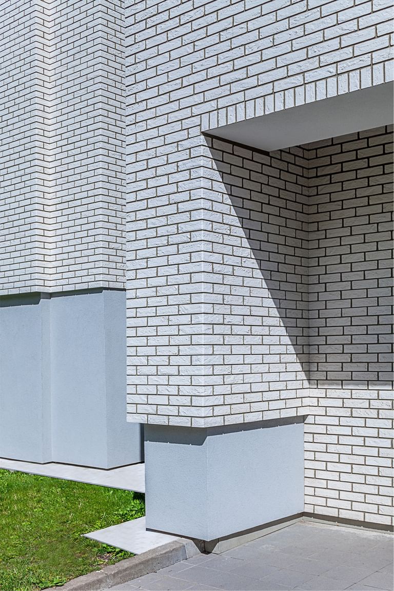 Elegante weiße Klinkerstruktur mit präzisem Fugenspiel und markanter Schattenwirkung