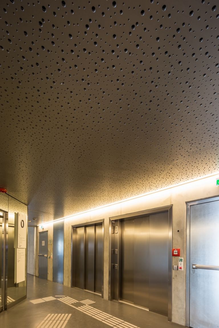 Minimalistischer, heller Korridor im Erdgeschoss der Wirtschaftsuniversität Wien mit Aufzügen und Beleuchtungselemente
