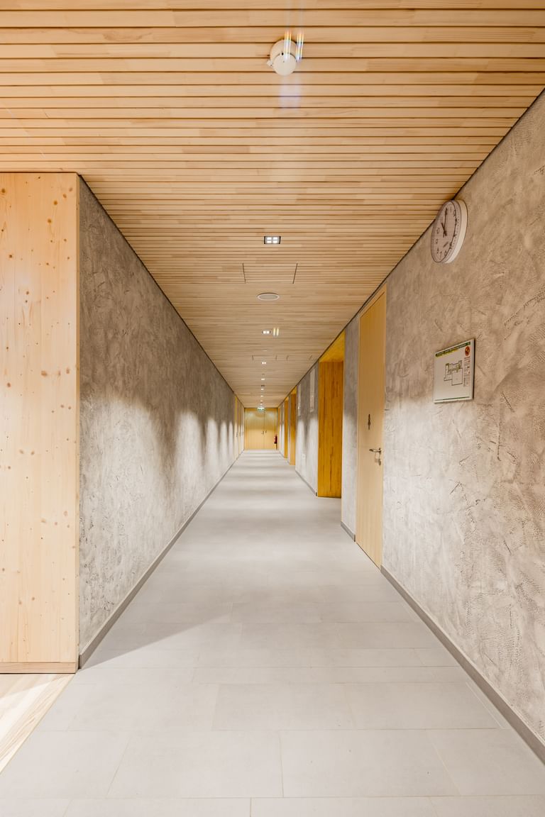 Langer Flur mit Holzdecke und Wänden in Betonoptik