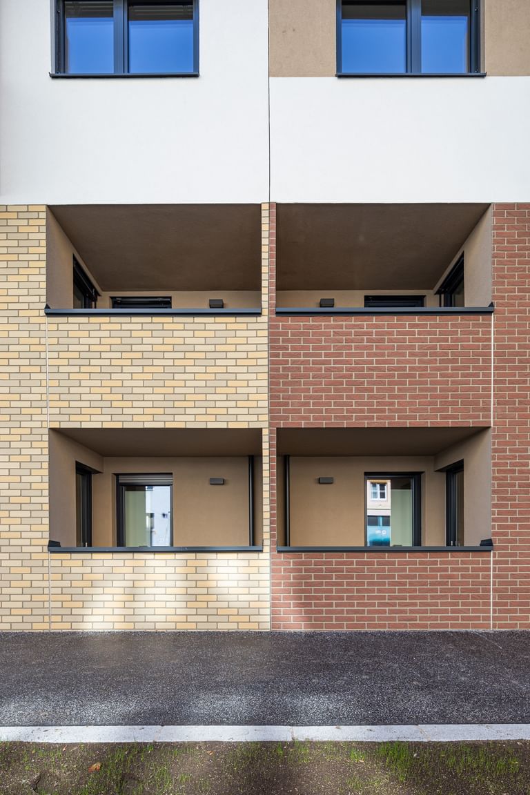 Außenansicht Mehrparteienhaus, Fassade in Klinkeroptik, links beige und rechts braun, mit Loggias