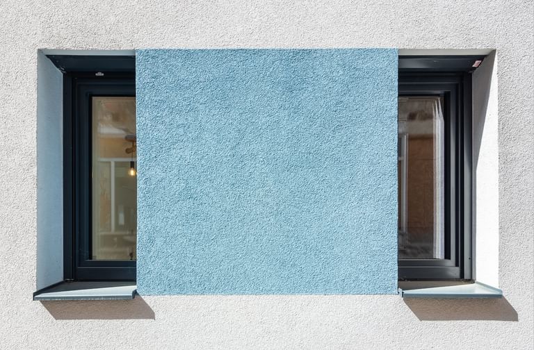 Schmale hohe Fenster mit türkiser Fassade