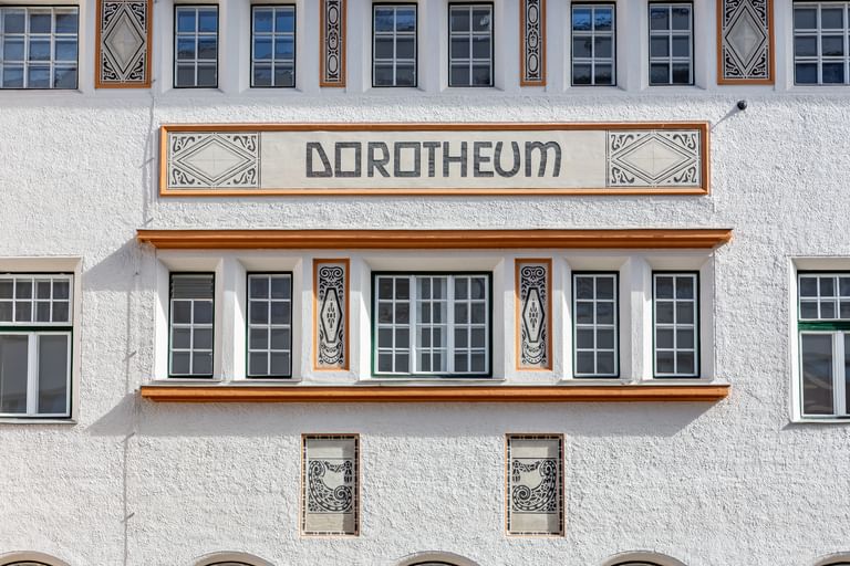 Detailreiche Jugendstilfassade des Dorotheum Linz mit aufwendig verzierten Fenstern, geometrischen Ornamenten und markanten orangefarbenen Zierelementen, restauriert mit Histolith-Farben