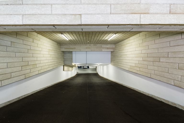 Tiefgarageneinfahrt mit Wänden in Ziegeloptik, schwarz Asphaltfläche