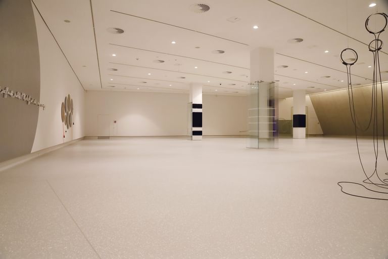 Moderner Ausstellungsraum mit weißen Wänden und Bodenbeschichtung im Schlossmuseum Linz