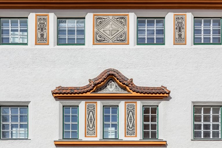 Detailreiche Jugendstilfassade des Dorotheum Linz mit aufwendig verzierten Fenstern, geometrischen Ornamenten und markanten orangefarbenen Zierelementen, restauriert mit Histolith-Farben