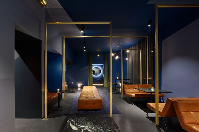 Lounge mit blauen Wänden, braunen Sesseln und goldenen Wandelementen