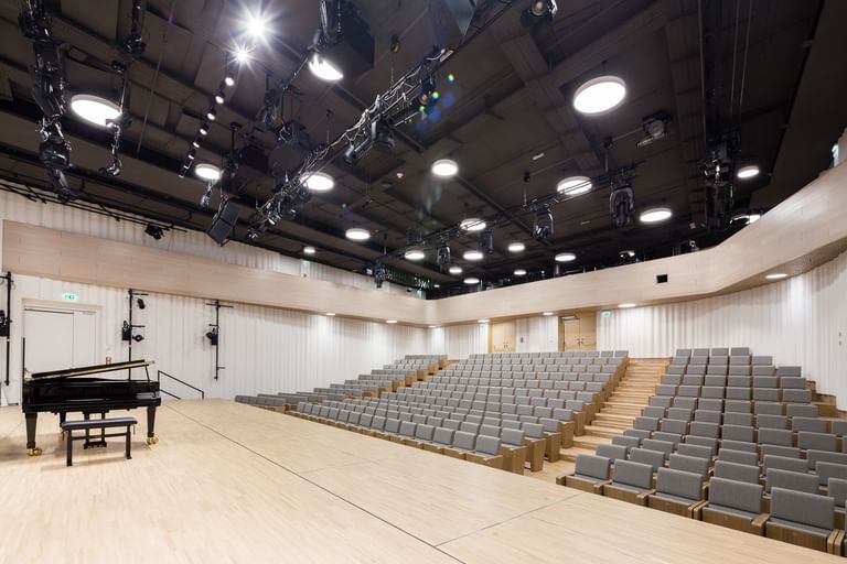 Großer Konzert- oder Vortragssaal in der Anton Bruckner Privatuniversität Linz mit Sitzreihen, einem schwarzen Flügel und klarer, moderner Raumgestaltung, vorbereitet für musikalische oder akademische Veranstaltungen.