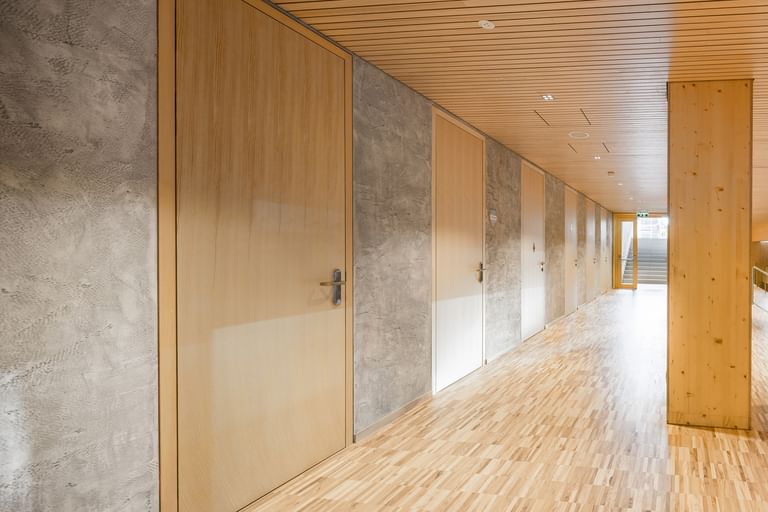 Flur einer Volkshochschule. Entlang des Flurs sind mehrere Türen aus Holz, die in weitere Räume führen.